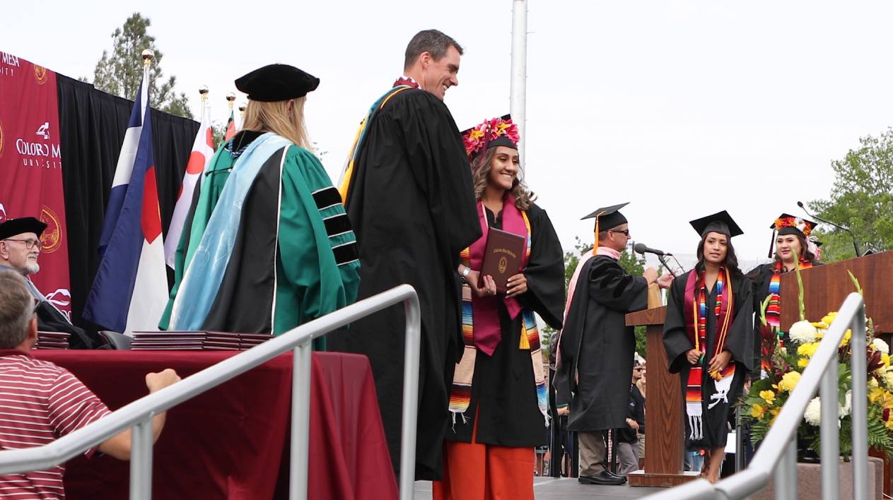 graduates claiming diploma on stage
